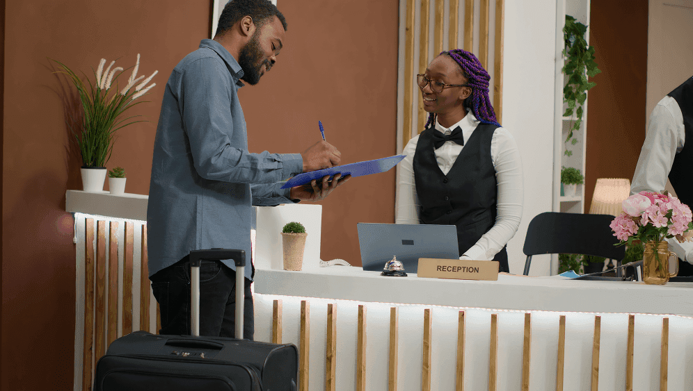 Guest signing in at a hotel reception desk with luggage nearby