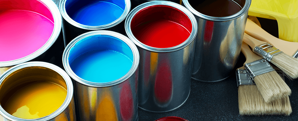Open paint cans in vibrant colours with brushes on a dark surface
